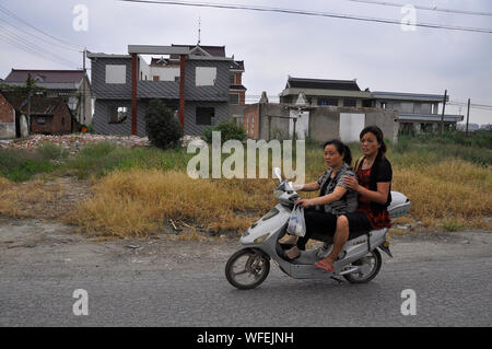 Chinese e-bike riders travel through an area that  is being redeveloped, Nantong China Stock Photo