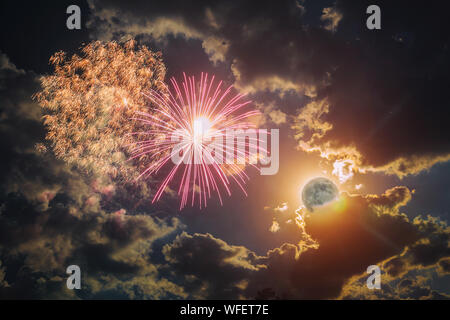 Amazing fireworks with the full moon in a dark night sky and clouds Stock Photo