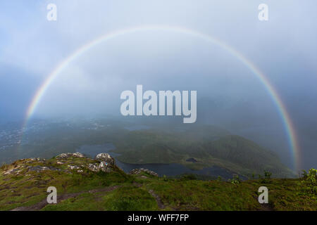 A rainbow seen from the peak of Tjeldbergtind during a storm Stock Photo
