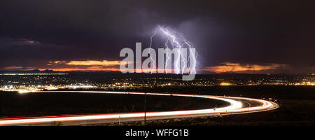 Cloud to ground lightning strikes in the Upper Valley of El Paso, Texas, USA, in August 2019, with curving light trails from Transmountain Road. Stock Photo