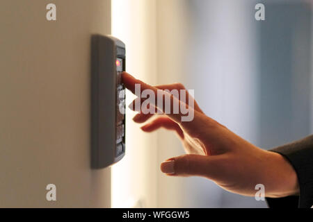 The woman presses the buttons of the code lock at the entrance to the room Stock Photo