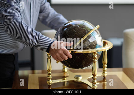 A man puts the globe on a table in a business office Stock Photo
