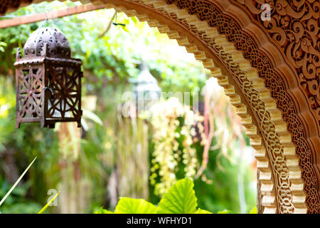 arch decorated with arabic ornaments with an interior green garden in the background Stock Photo