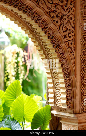 arch decorated with arabic ornaments with an interior green garden in the background Stock Photo