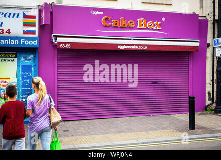 two people walking near closed shuttered shop in Rotherham Stock Photo