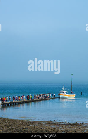 People holiday makers and  tourists queuing on the jetty for a boat ride around the bay at the North Wales seaside resort of Llandudno Stock Photo