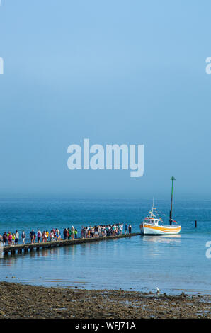 People holiday makers and  tourists queuing on the jetty for a boat ride around the bay at the North Wales seaside resort of Llandudno Stock Photo
