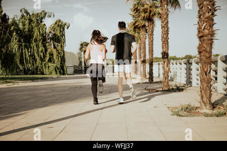 Couple of Caucasian men and Latina women run. Photographic shot from the back Stock Photo