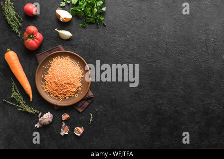 Lentil soup ingredients: red lentil, seasonal organic vegetables on black table, top view, copy space. Cooking autum, winter seasonal soups and dishes Stock Photo