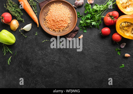 Autumn cooking background with red lentil, seasonal organic vegetables on black stone table, top view, copy space. Ingredients for autum seasonal soup Stock Photo