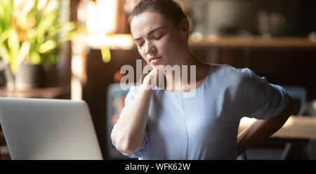 Stressed young business woman feeling backpain working on laptop Stock Photo