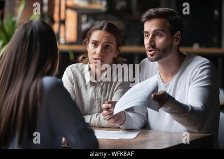 Angry couple arguing with bank manager complain on bad contract Stock Photo