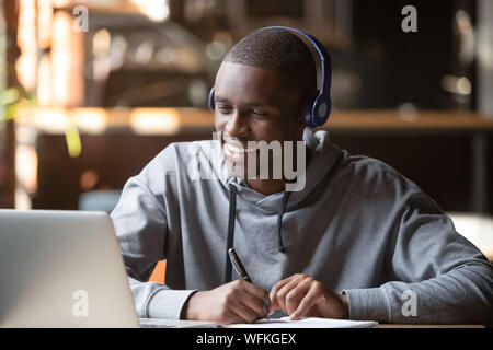 Smiling african young man student wearing headphones study online Stock Photo
