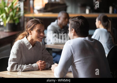 Happy young couple smiling chatting sitting at cafe table Stock Photo