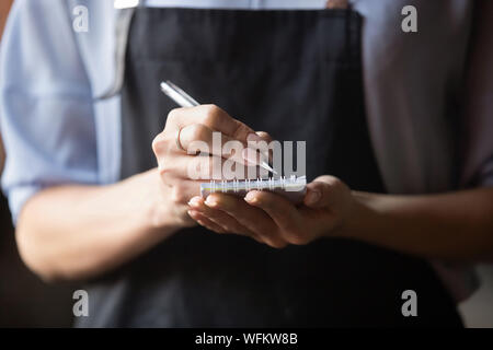 Waitress wear apron holding notepad pen write notes take order Stock Photo