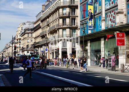 Sunday activity along rue de Rivoli with shoppers, shopfronts, bikers, and traffic, Paris, France. Stock Photo