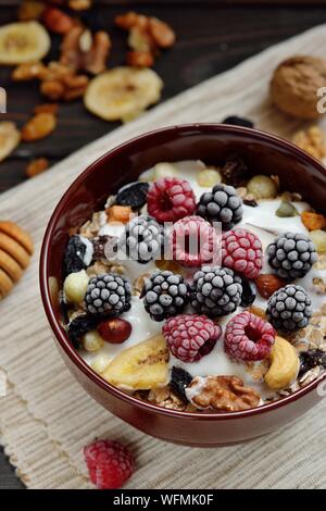 Granola with yougurt, nuts, fresh berries on wooden brown background. Breakfast tabel Stock Photo