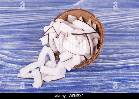 Coconut pieces in bowl on blue background. Fresh coconut slices Stock Photo