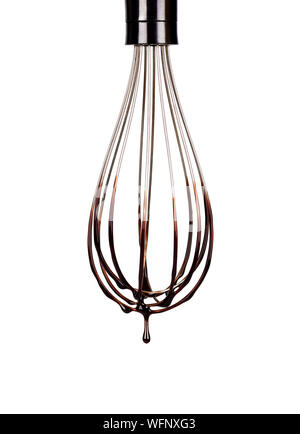 Cookery wire whisk with splashing chocolate isolated on white background with clipping path. Chocolate drop Stock Photo