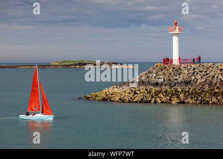 Ireland, Fingal County, northern suburbs of Dublin, Howth, sailboat entering the harbor, passing beacon lighthouse Stock Photo