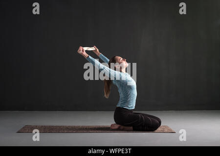 Sporty girl doing variation of asana Viparita Karani using belt