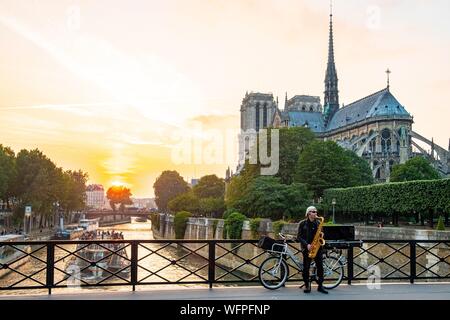 France, Paris, area listed as World Heritage by UNESCO, Ile de la Cite, saxophonist on the bridge of the Archeveche with Notre Dame de Paris Stock Photo