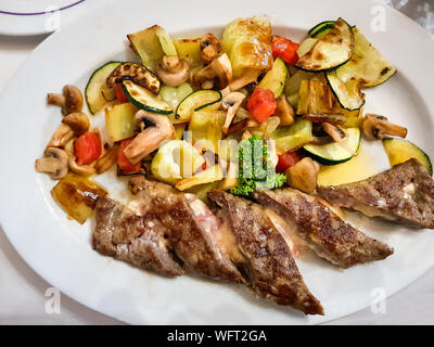 Main course. Pork stuffed with cheese. Attachment is a stewed vegetable. Mushrooms, tomatoes, peppers, zucchini. Stock Photo