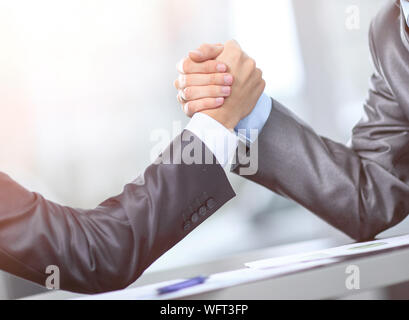 Two businessmen press hands with each other in the foreground. Fighting between entrepreneurs. armwrestling Stock Photo