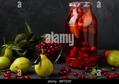 Dogwood compote with pears in jar on a dark background, horizontal orientation Stock Photo