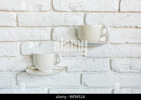 coffee cups as lamp decorations on a white brick wall in modern loft cafe Stock Photo