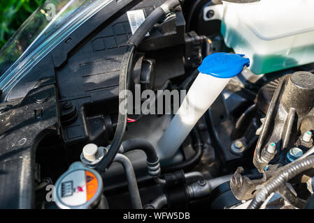 Windshield washer fluid reservoir with blue stopper, located in the engine compartment. Stock Photo