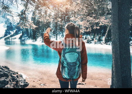 young woman with backpack taking a selfie on the lake at sunset Stock Photo