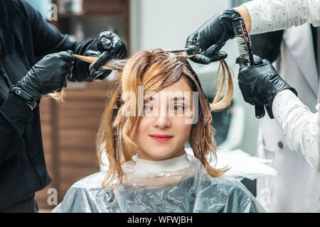 Professional hairdresser is dying female hair in a beauty salon Stock Photo