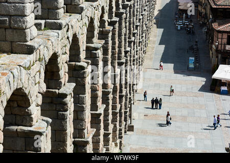 SEGOVIA, SPAIN - APRIL 25, 2018: Picturesque view in Segovia with tourists walking next to the Roman Aqueduct. Stock Photo