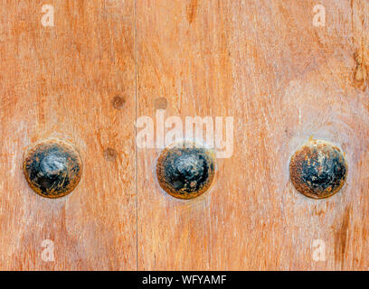 Macro shot of three rusty bolts on an old, heavy wooden door Stock Photo