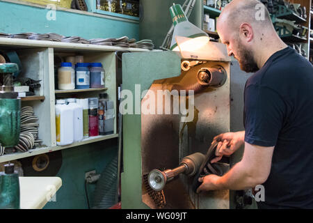 A male shoemaker grinding and shaping a sandal in his workshop. Stock Photo