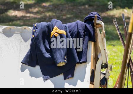 Union army jacket and gear lay on a white canvas tent during an American Civil War Reenactment Stock Photo