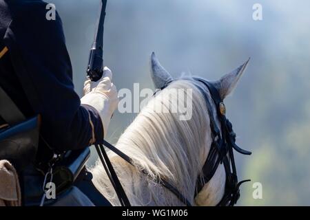 A man dressed as a union general riding a white horse into a cannon smoke covered battlefield during an American Civil War reenactment Stock Photo