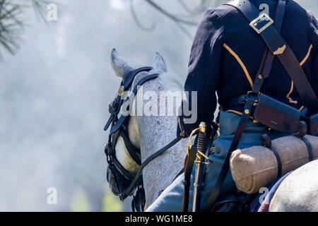 A man dressed as a union general riding a white horse into a cannon smoke covered battlefield during an American Civil War reenactment Stock Photo