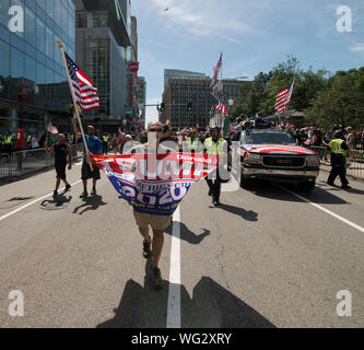 Boston, MA, USA.  31st August 2019.  Hundreds took part in the Straight Pride Parade through central Boston, MA.  The Straight Pride marchers, supporters of U.S. President Donald Trump, were outnumbered by anti-Trump and gay rights supporters who lined the streets along the Straight Pride march from Copley Square to Boston City Hall Plaza.  Hundreds of Boston Police separated the marchers from the anti-straight pride counter demonstrators along the parade route and at City Hall Plaza. Photo shows  man leading the march with a TRUMP 2020 banner. Credit: Chuck Nacke / Alamy Live News Stock Photo