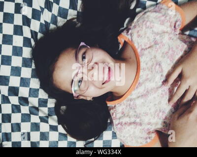 High Angle Portrait Of Smiling Teenage Girl Lying On Bed