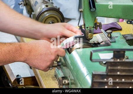 Male shoemaker hands skiving leather with a vintage skiving machine. Stock Photo