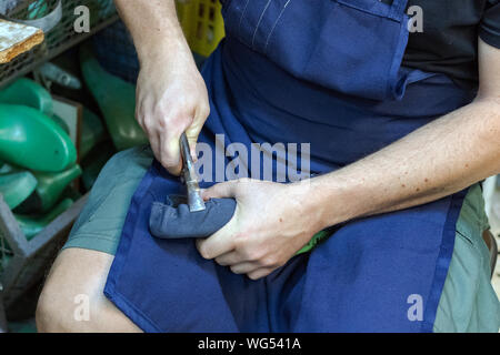 A male shoemaker working on a sole, bending - nailing nails with a shoe plier. Stock Photo