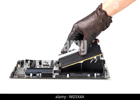 hand in black glove installing memory module with heatsink in pc motherboard isolated on white background with selective focus Stock Photo