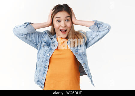 Amused glad cute asian blond girl receive wonderful exciting news grab head smiling broadly toothy thrilled smile reacting amazing awesome positive Stock Photo