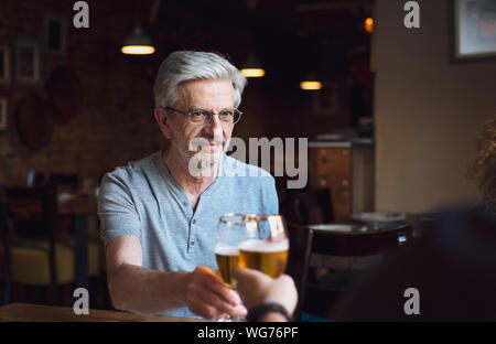 Senior man toasting with a beer in the bar Stock Photo