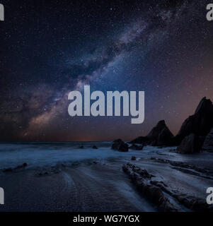 Beautiful composite landscape image of Mily Way core over sea rocks and cliffs with long exposure tide on beach Stock Photo