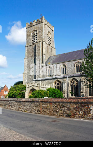 A view of the tower and south porch of the parish Church of St Nicholas by the A149 coast road at Wells-next-the-Sea, Norfolk, England, UK, Europe. Stock Photo