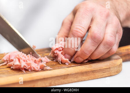 Chef slicing ham on wooden table . Stock Photo