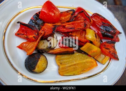 Baked vegetables, peppers, eggplant, squash, on a white platter with a gold border. Stock Photo